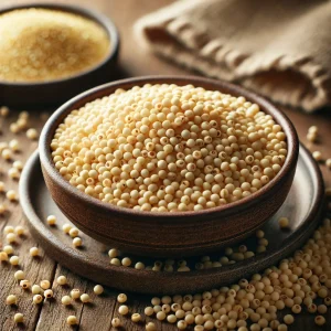 The picture shows raw, yellowish, small millet grains in a ceramic bowl, with some grains scattered on the wooden surface.